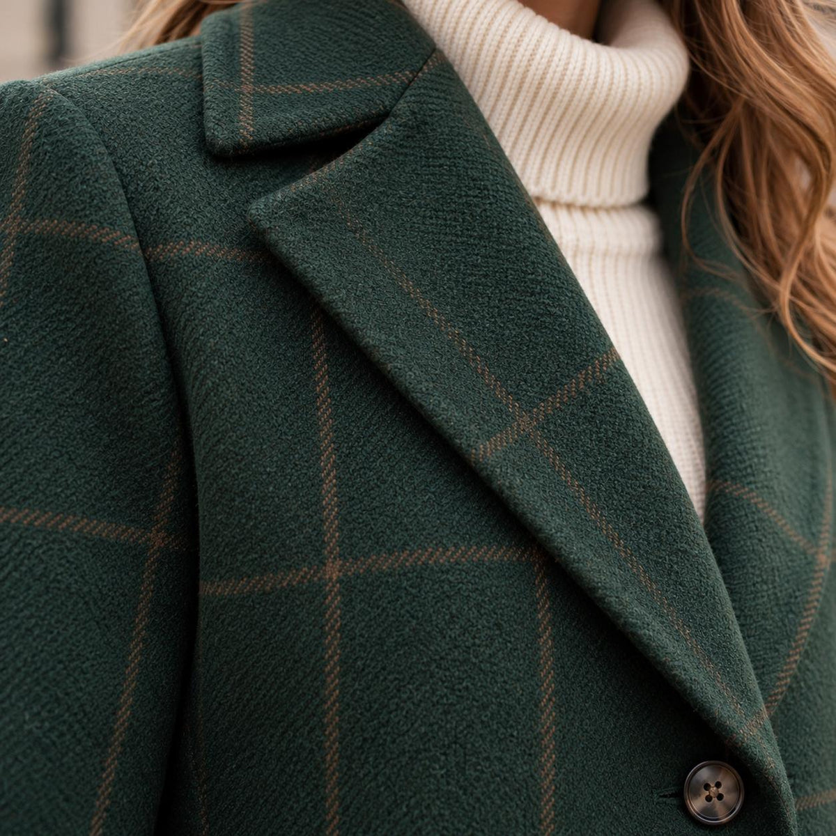 Close-up of the dark green tweed plaid fabric, lapel and horn button