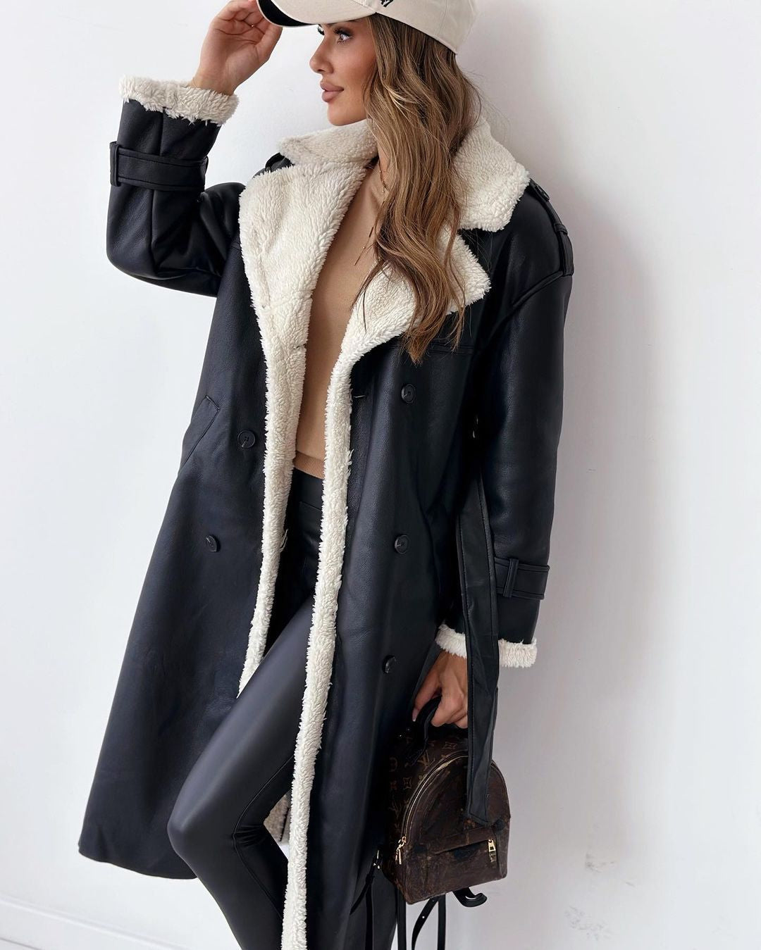 Woman wearing the black double-breasted teddy coat with cream shearling lapels, front view