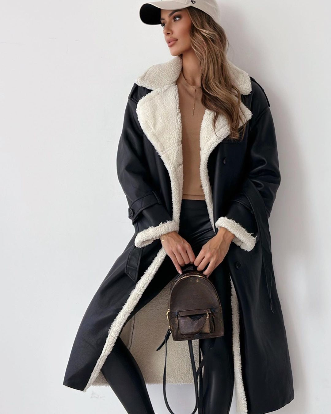 Black teddy coat worn open over a cream knit and matching trousers