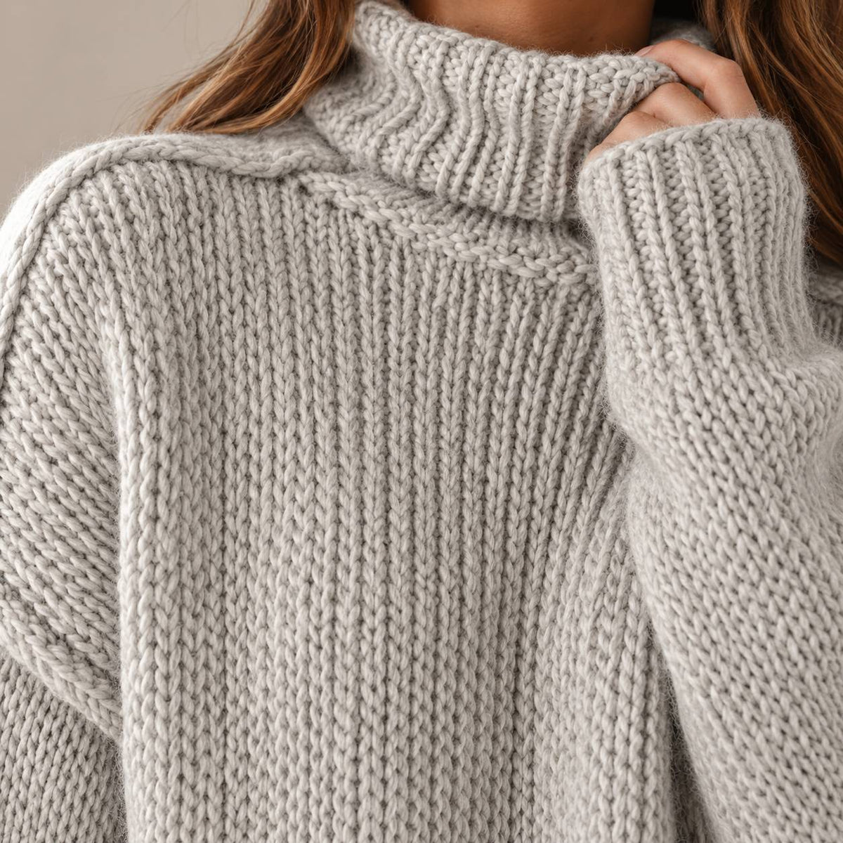 Close view of the folded turtleneck collar on the grey chunky knit sweater