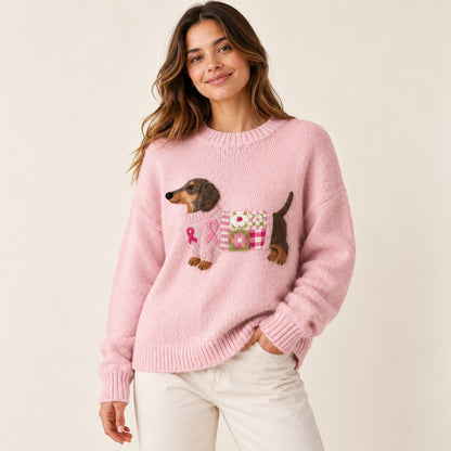 Woman wearing a pink knit sweater with an embroidered dachshund motif