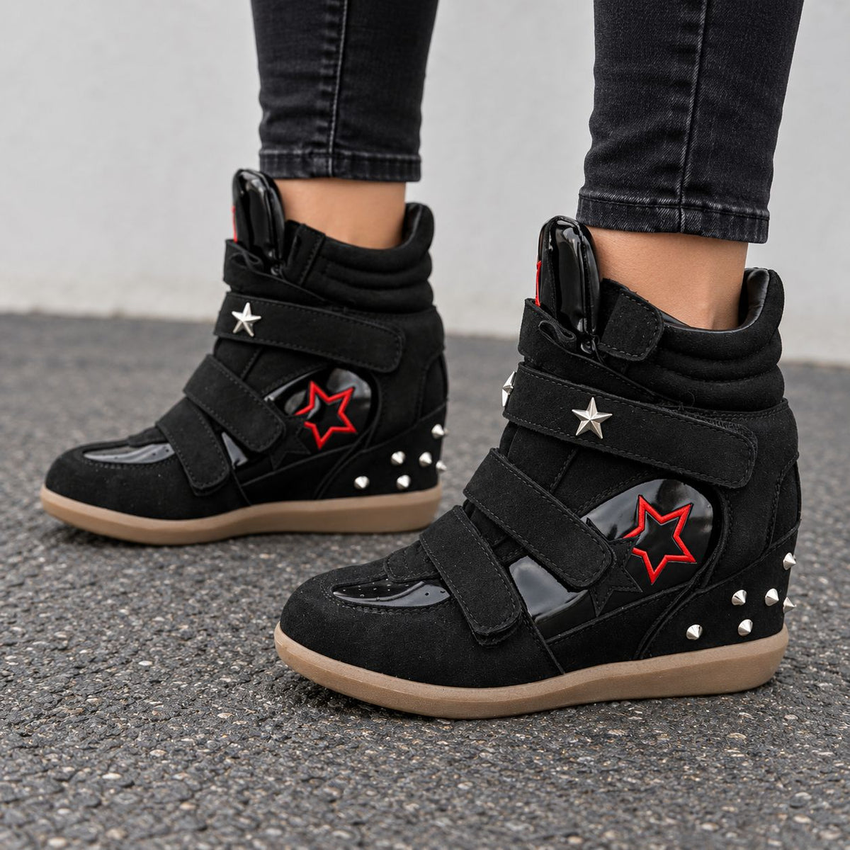 Black studded star high-top wedge sneakers with red star detail and silver studs, worn with black jeans