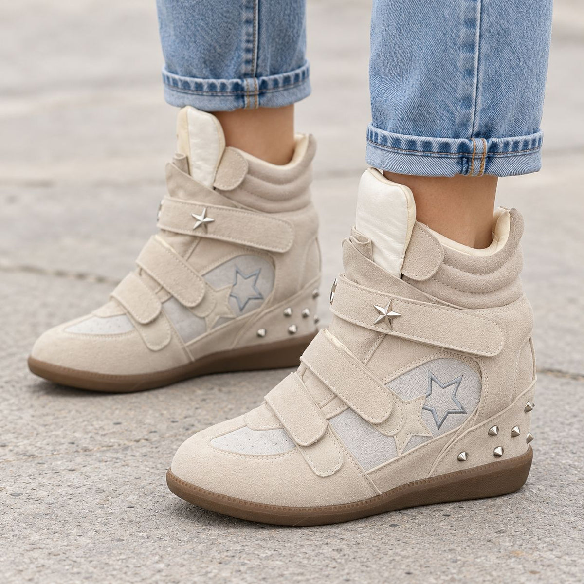 Cream studded star high-top wedge sneakers with silver star studs, worn with cuffed blue jeans