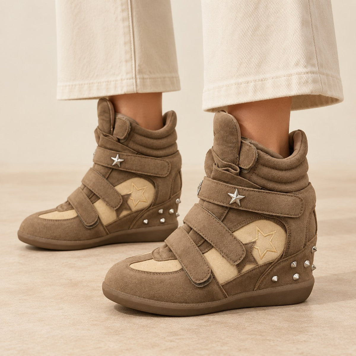 Khaki studded star high-top wedge sneakers with silver star studs, worn with cream wide-leg trousers